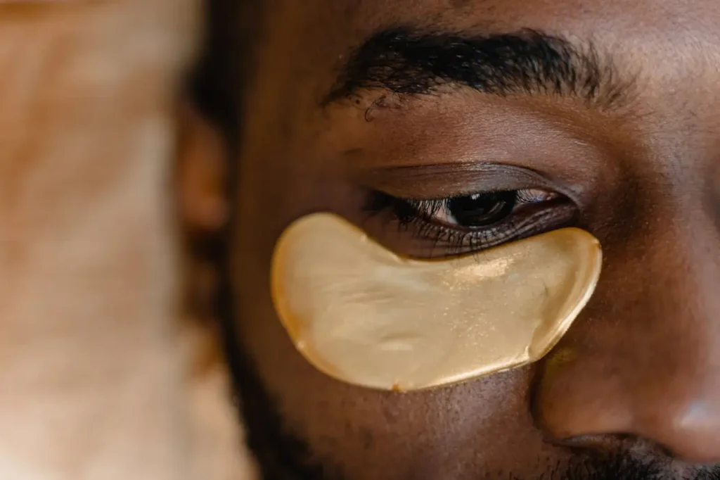 Close-up of a man's eye with a gold under-eye patch, representing skincare and botox eyebrow lift treatment for reducing fine lines and rejuvenating the eye area.