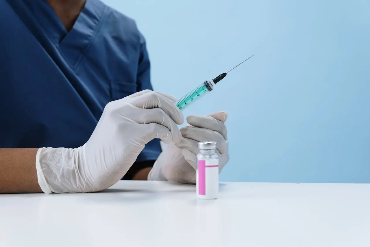 Medical professional wearing gloves preparing a syringe with botox solution from a vial in a clinical setting.