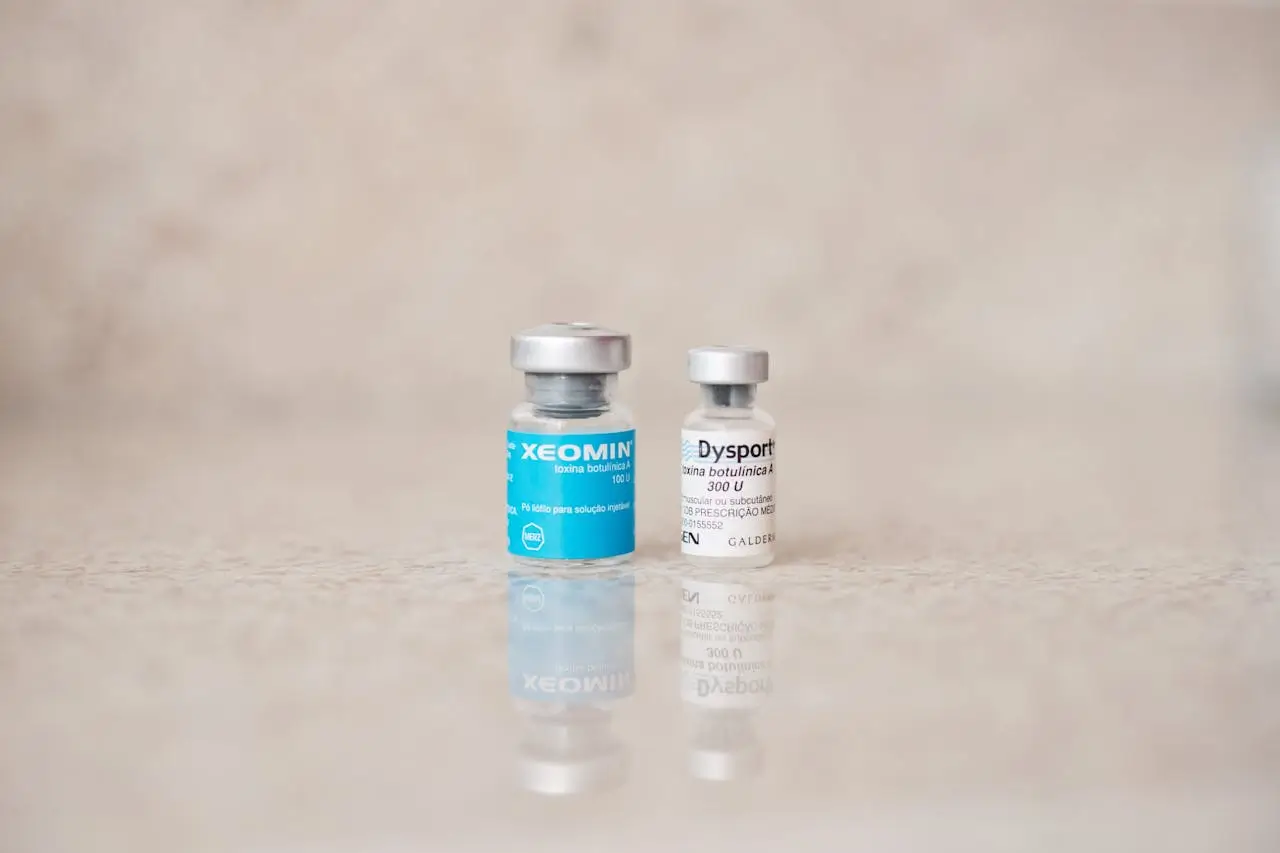Close-up of Xeomin and Dysport botox vials placed on a reflective surface, representing botox treatment products and how they work.