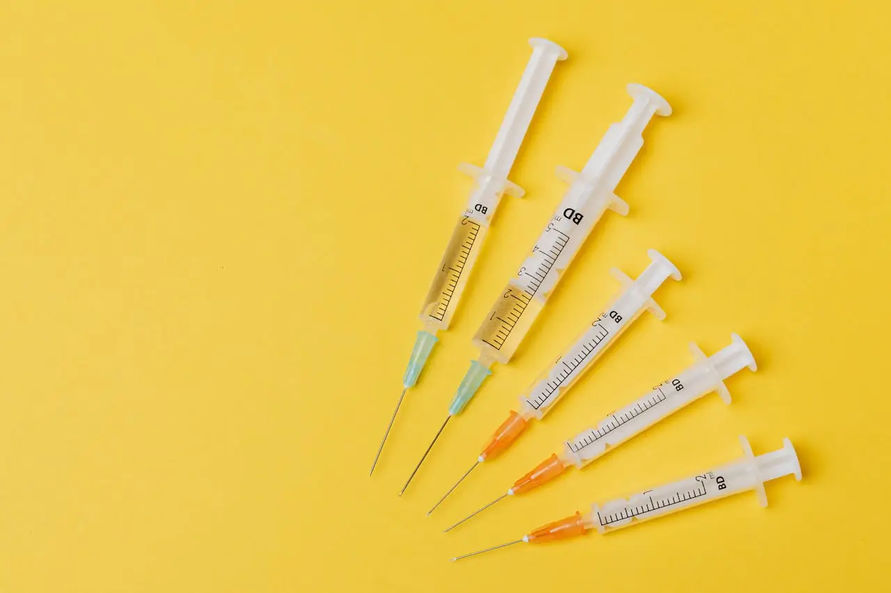 Multiple medical syringes filled with solution arranged on a yellow background, representing botox and the question of whether it is a poison.