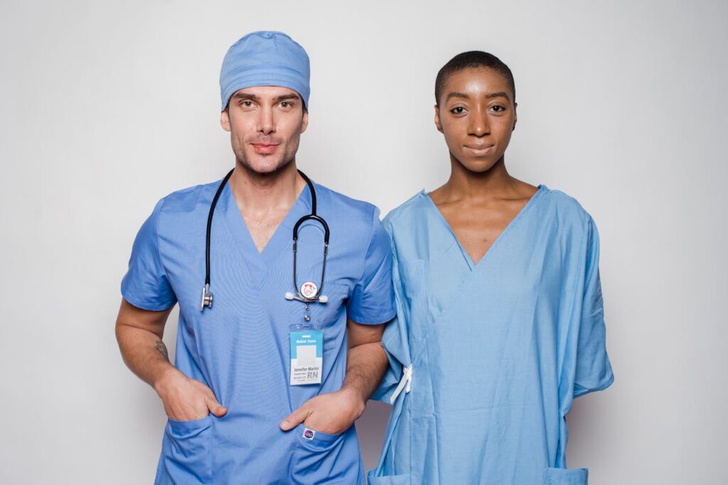 Two trained medical professionals wearing blue scrubs standing confidently, representing qualified healthcare staff and clinical expertise.