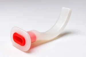 Hyper-realistic 3D image of a transparent Guedel airway with a red bite block, curved semi-transparent plastic body, and smooth glossy finish on a white background.