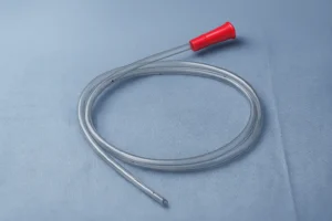 Hyper-realistic image of a transparent nasogastric tube with a red funnel connector, smooth coiled tubing, and visible lateral eye holes, displayed on a soft blue clinical drape under diffused surgical lighting.