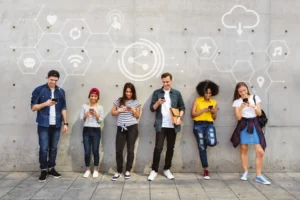 A diverse group of young adults standing together, engaged in social media on their smartphones, symbolizing the importance of social connections in the digital age.