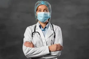 A female clinician wearing a medical mask and hairnet, representing a healthcare professional examining or diagnosing skin conditions.