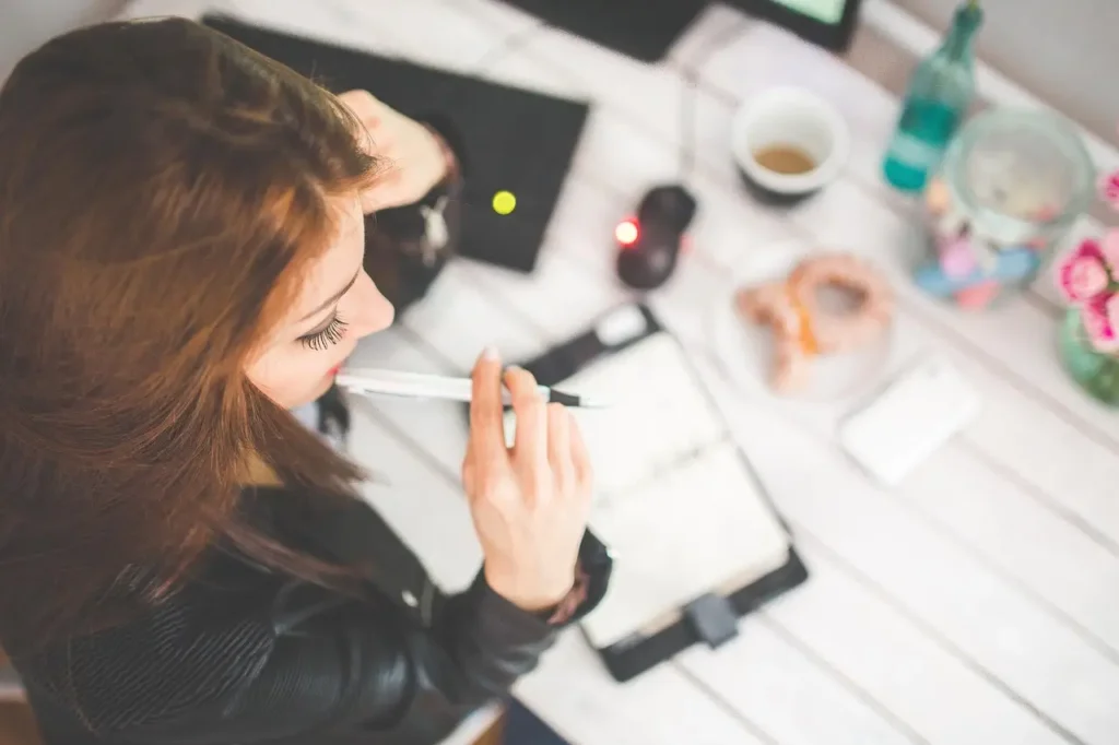 A woman working at a desk with focus and planning, representing higher productivity achieved through good sleep and healthy habits.