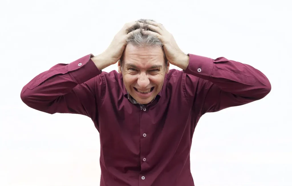 A stressed man holding his head representing oxidative stress caused by free radicals