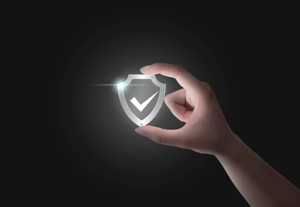 Human hand holding a glowing shield with a checkmark icon — symbolizing skin protection and prevention from warts and skin tags through good hygiene and skincare habits.