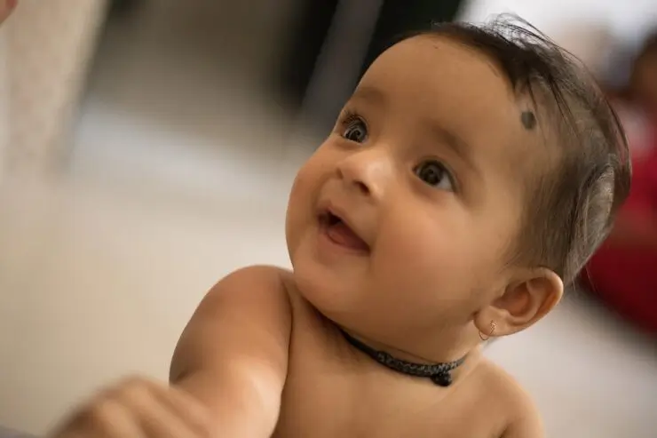 A smiling newborn baby with a small skin mark on the face, representing harmless skin tags that can appear in infants.