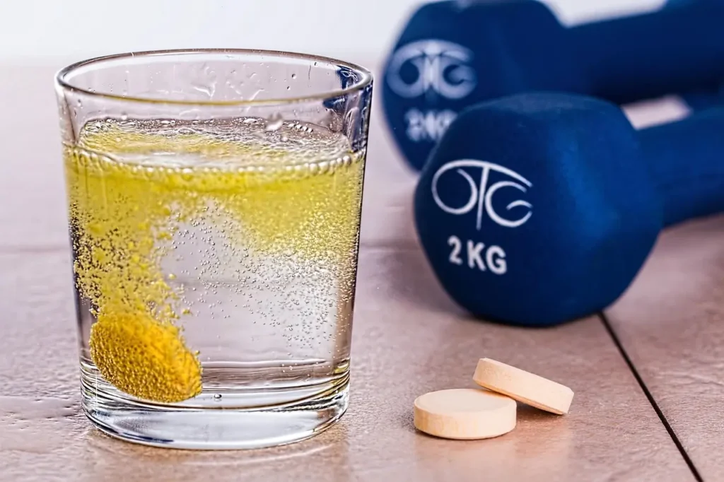 Effervescent vitamin supplement dissolving in water with dumbbells in the background representing antioxidants and fitness