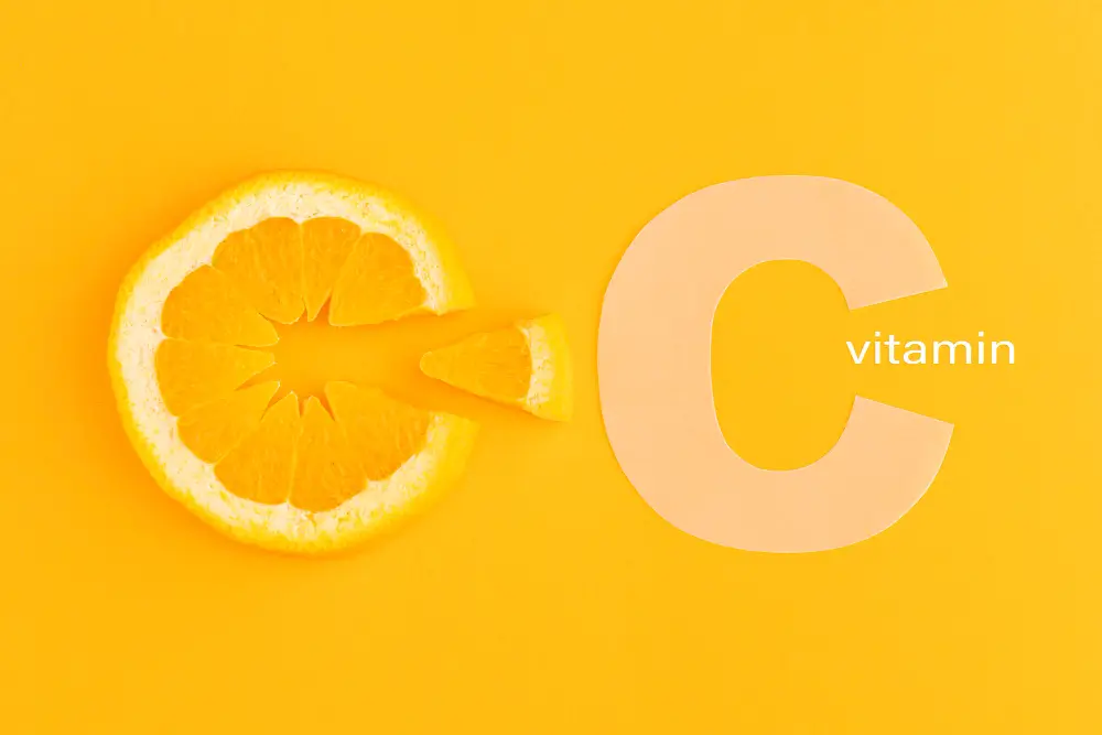 Creative image of an orange slice arranged in the shape of the letter C on a bright yellow background, symbolizing vitamin C.