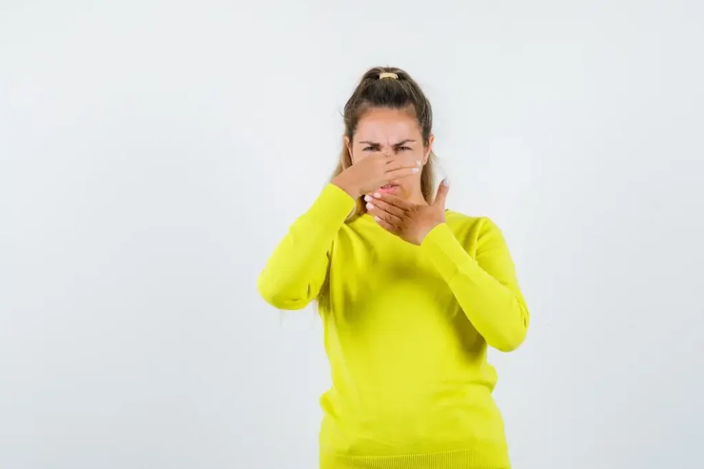 Woman covering her mouth and nose because of bad breath which may be caused by cavities