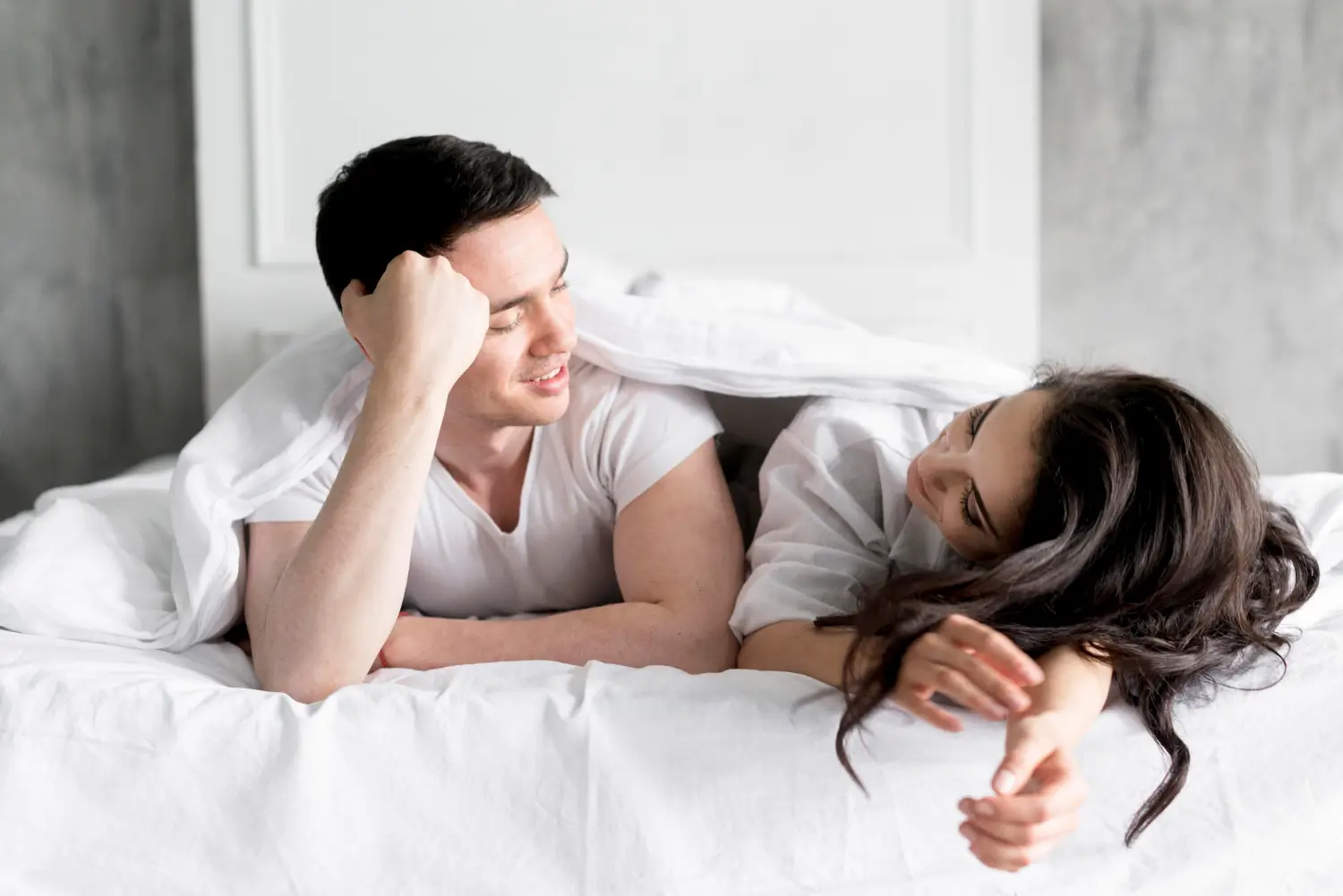 Couple lying in bed together representing sexual activity and fertility awareness related to pregnancy risk during menstrual cycle